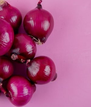 close-up view of red onions on left side and purple background with copy space close-up view of red onions on left side and purple background with copy space